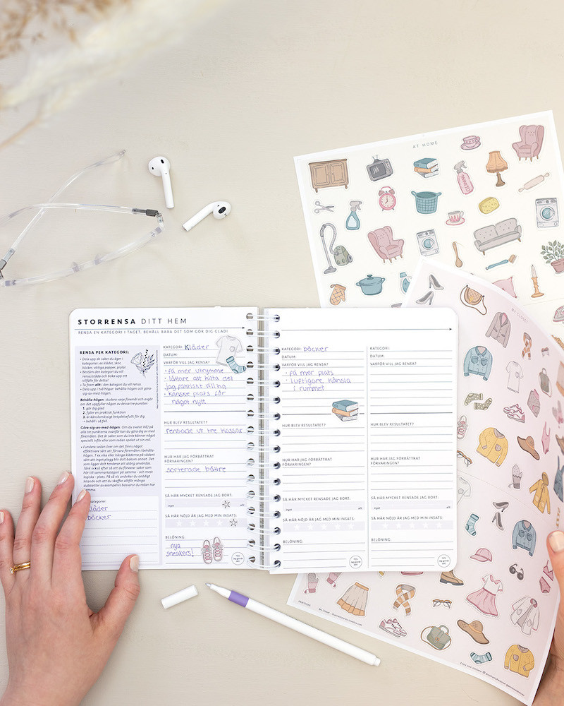 Temasidan Storrensa ditt hem uppslagen i en almanacka. Bredvid ligger en Fineliner Uni Emott-penna och klistermärken från arken My Closet och At home