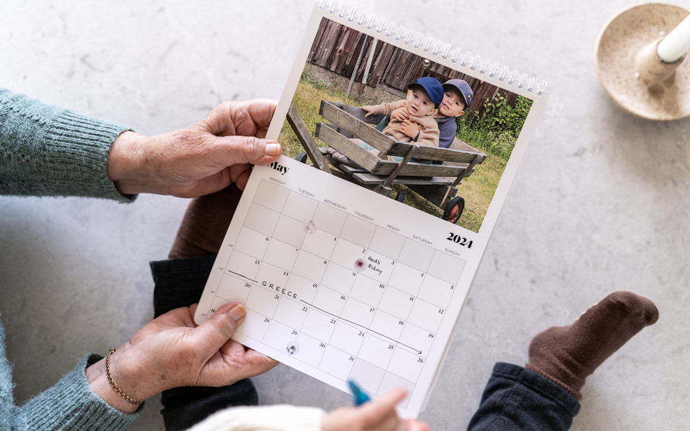 Hender som holder i en fotokalender med et bilde på to barn