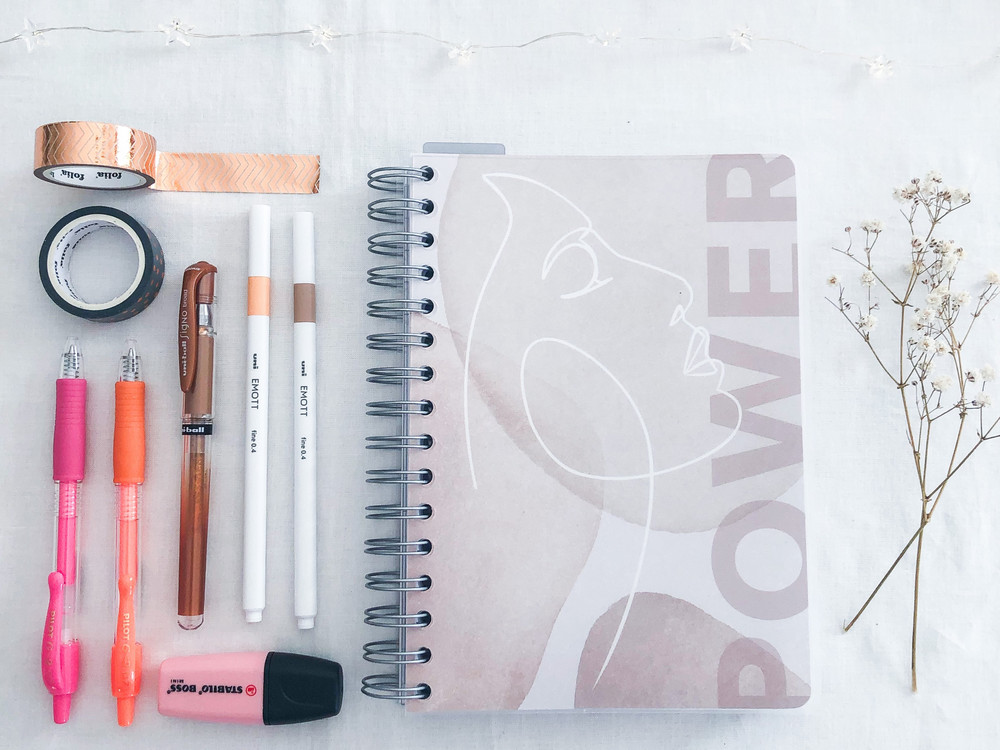 Flatlay av forskjellige bullet journal forsyninger inkludert penner, klistremerker og washiteip