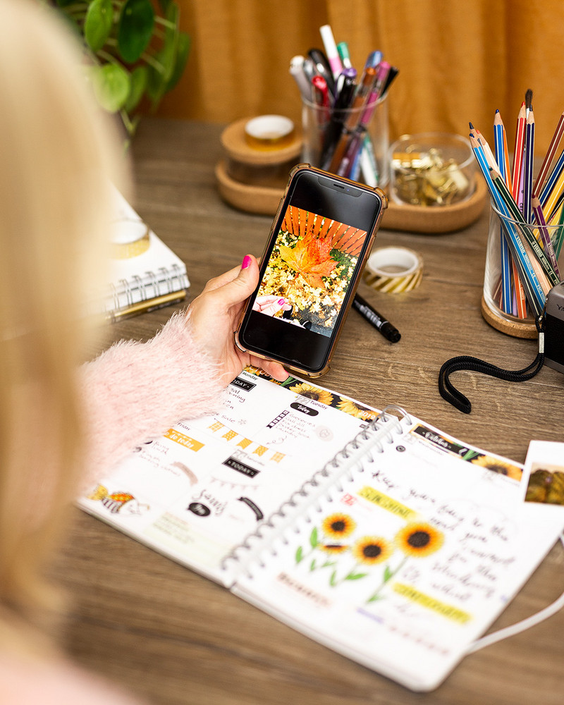 Notebook and mobile phone on a desk with pens and stickers